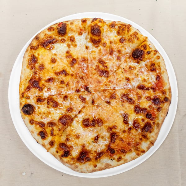 Large cheese pizza with a golden, blistered crust served on a white plate.