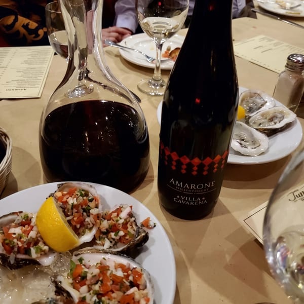 A table set with oysters, a decanter of red wine, and a bottle of Amarone Villa Cavarena.